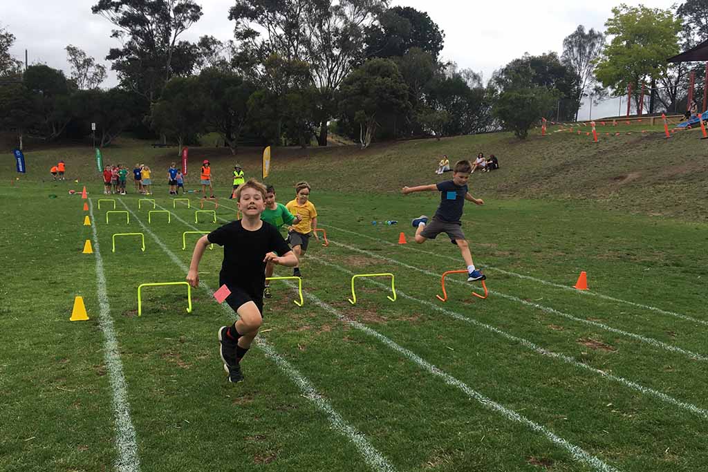 Sports day, students running over hurdles.